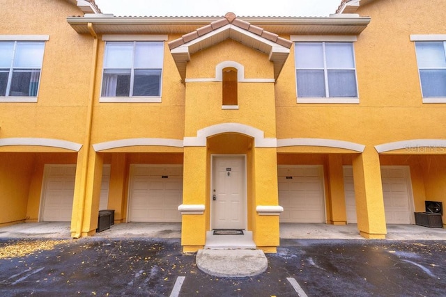 view of property featuring stucco siding, an attached garage, and a tile roof