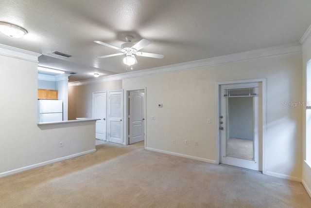 spare room featuring visible vents, light carpet, ornamental molding, a ceiling fan, and baseboards