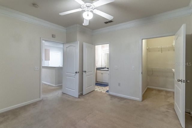 unfurnished bedroom featuring baseboards, visible vents, ornamental molding, a spacious closet, and light colored carpet