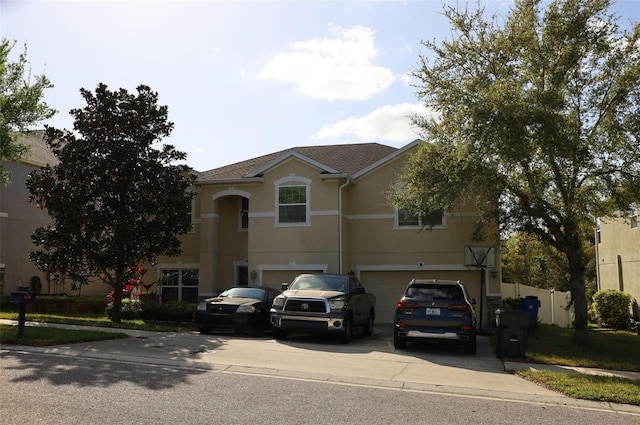 view of front of house with concrete driveway, fence, a garage, and stucco siding