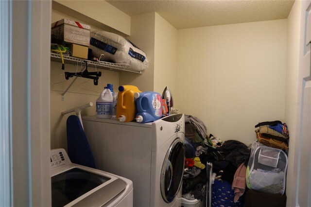 laundry room with a textured ceiling, washing machine and dryer, and laundry area