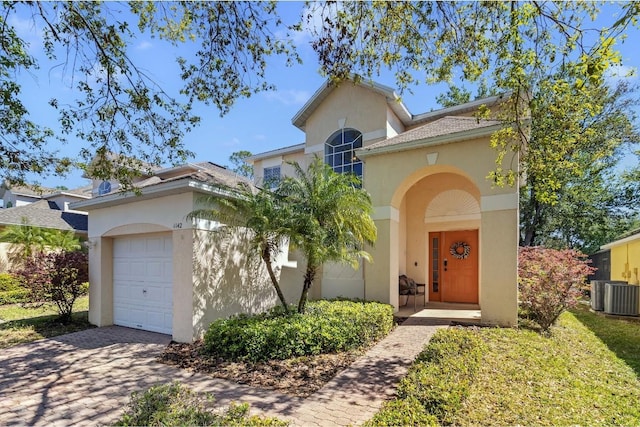 mediterranean / spanish-style house featuring stucco siding, driveway, central air condition unit, and an attached garage