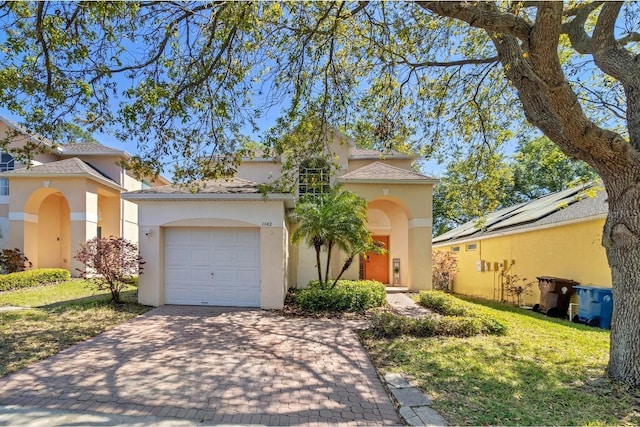 mediterranean / spanish-style home featuring a front yard, decorative driveway, a garage, and stucco siding