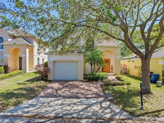 mediterranean / spanish-style house featuring stucco siding, driveway, a shingled roof, a front yard, and an attached garage