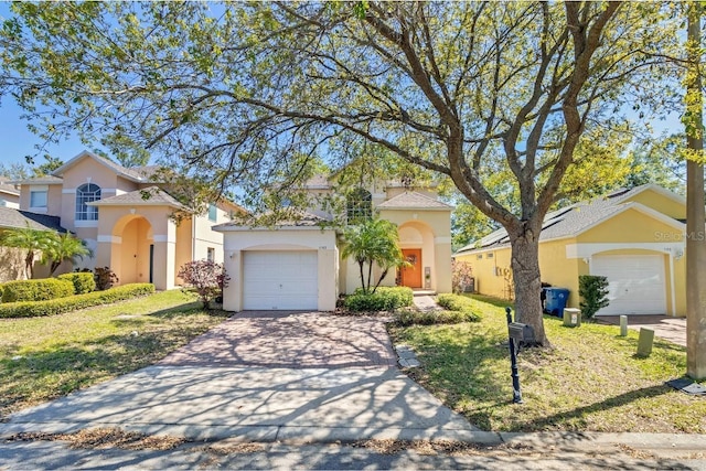 mediterranean / spanish house featuring stucco siding, a front lawn, an attached garage, and driveway