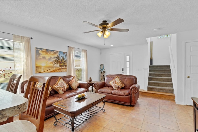 living room with stairway, light tile patterned flooring, a ceiling fan, and a textured ceiling