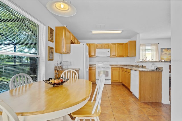 kitchen featuring light countertops, light tile patterned floors, a peninsula, white appliances, and a sink