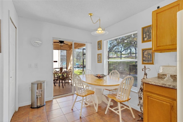 dining space featuring light tile patterned floors, baseboards, a textured ceiling, and ceiling fan