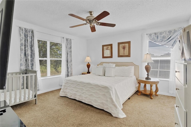 carpeted bedroom featuring baseboards, a textured ceiling, and a ceiling fan