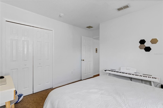 carpeted bedroom featuring visible vents, baseboards, a textured ceiling, and a closet