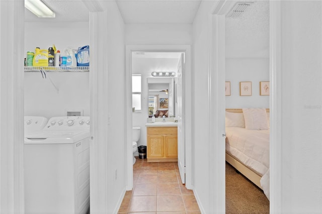 laundry room featuring light tile patterned floors, visible vents, laundry area, separate washer and dryer, and a sink