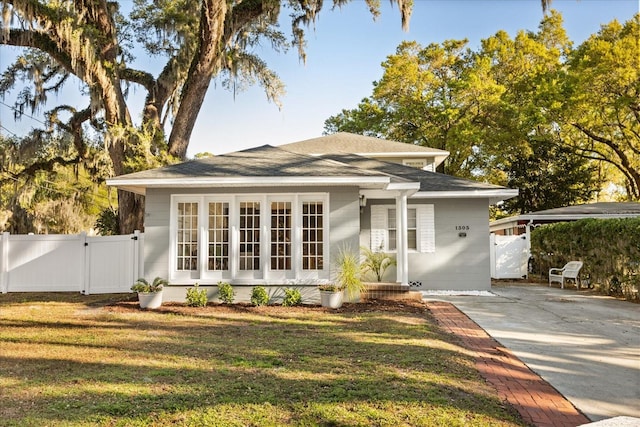 view of front of house with fence, a shingled roof, a front lawn, and a gate