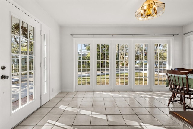 entryway with light tile patterned floors, a healthy amount of sunlight, and a chandelier