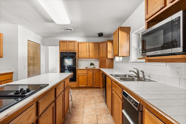 kitchen featuring a sink, black appliances, tile counters, and light tile patterned flooring