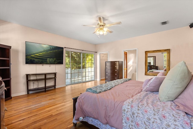 bedroom with wood finished floors, visible vents, baseboards, access to outside, and connected bathroom