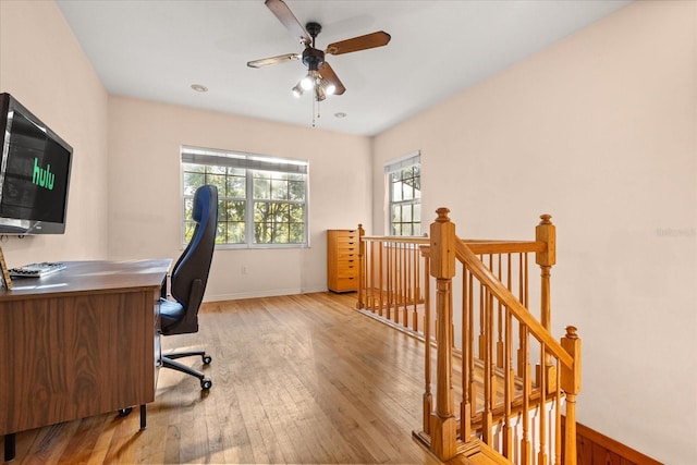 home office with light wood-type flooring and a ceiling fan