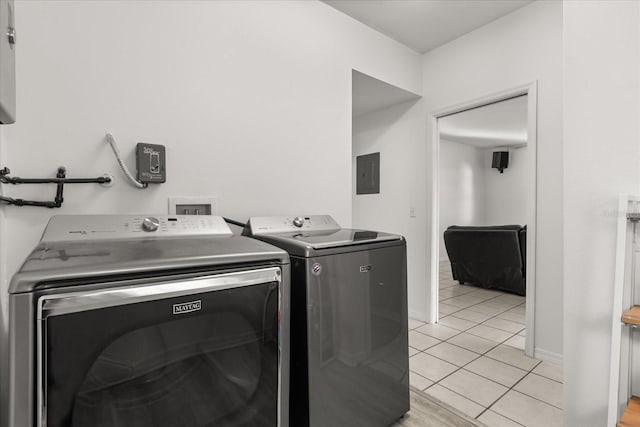 clothes washing area with electric panel, light tile patterned floors, baseboards, laundry area, and washing machine and clothes dryer