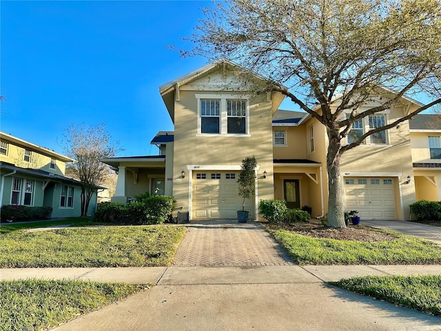 traditional-style home with stucco siding, decorative driveway, and a garage