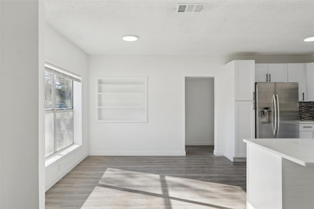 kitchen featuring visible vents, a textured ceiling, light wood-type flooring, and stainless steel fridge with ice dispenser