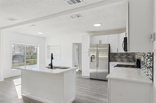 kitchen with visible vents, stainless steel refrigerator with ice dispenser, a sink, black microwave, and stove