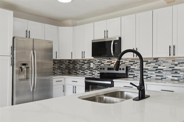 kitchen with decorative backsplash, appliances with stainless steel finishes, white cabinetry, and a sink