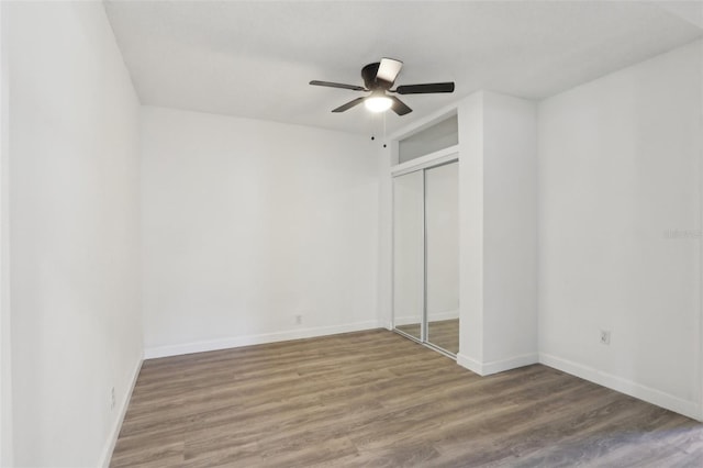 unfurnished bedroom featuring ceiling fan, wood finished floors, a closet, and baseboards