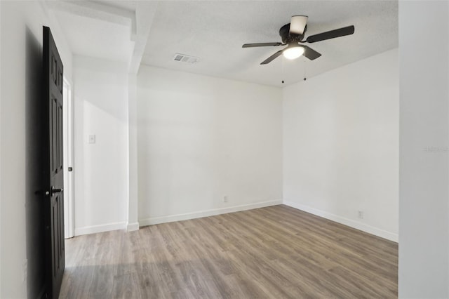 unfurnished room with ceiling fan, visible vents, baseboards, and wood finished floors