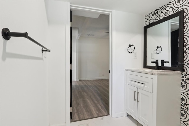 bathroom with baseboards, wood finished floors, and vanity