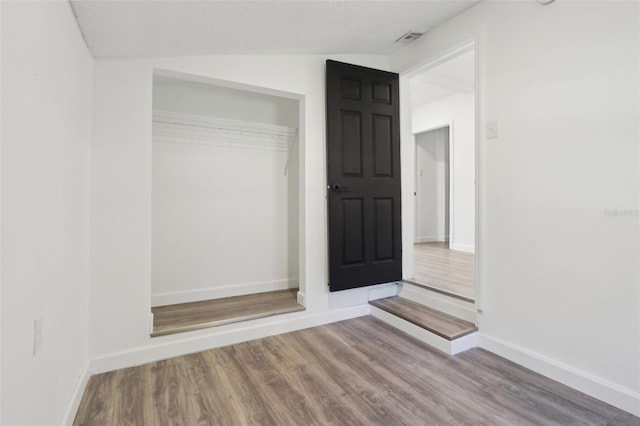 unfurnished bedroom with a closet, visible vents, baseboards, and wood finished floors