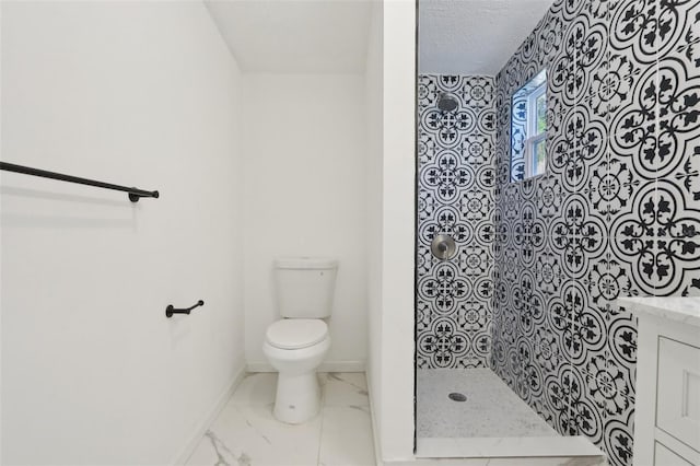 bathroom featuring toilet, marble finish floor, a tile shower, baseboards, and vanity