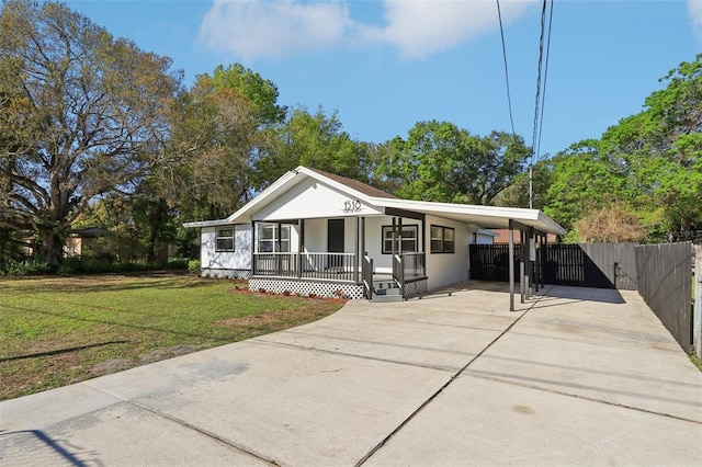 view of front of home featuring an attached carport, fence, a front yard, covered porch, and driveway