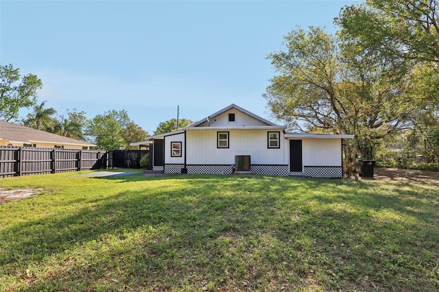 rear view of property featuring a lawn, central AC unit, and fence private yard