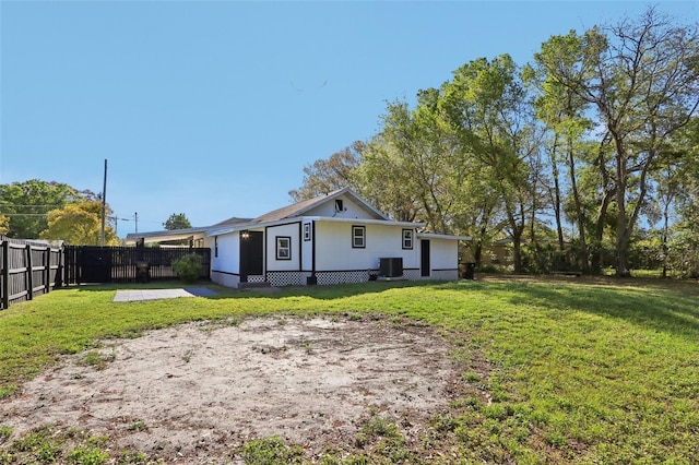 rear view of property with cooling unit, a lawn, and fence