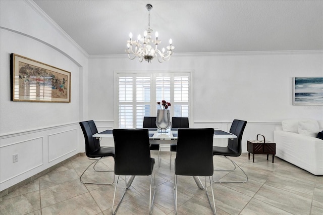 dining room with a wainscoted wall, a notable chandelier, crown molding, and a decorative wall