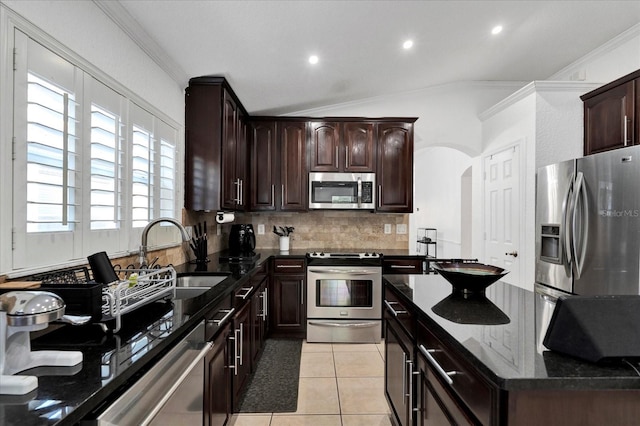 kitchen with tasteful backsplash, light tile patterned flooring, arched walkways, stainless steel appliances, and a sink