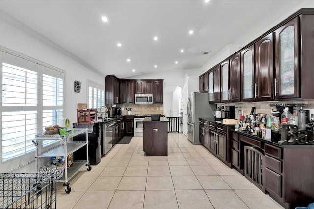 kitchen with a center island, decorative backsplash, appliances with stainless steel finishes, light tile patterned flooring, and arched walkways