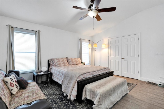 bedroom featuring vaulted ceiling, multiple windows, wood finished floors, and baseboards