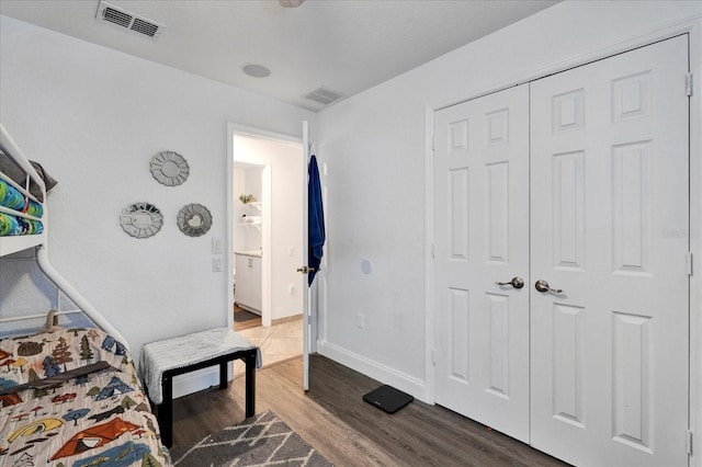 bedroom featuring a closet, visible vents, baseboards, and wood finished floors