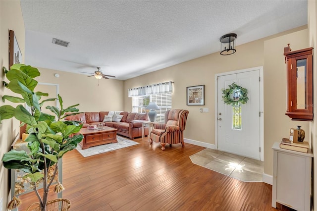 entrance foyer featuring visible vents, baseboards, wood finished floors, a textured ceiling, and a ceiling fan