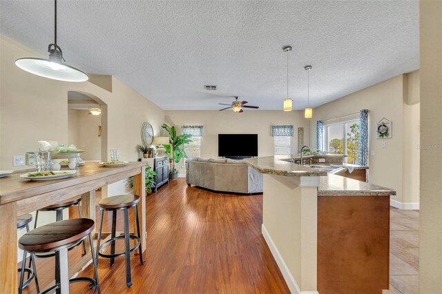 kitchen with visible vents, ceiling fan, a wealth of natural light, arched walkways, and a sink