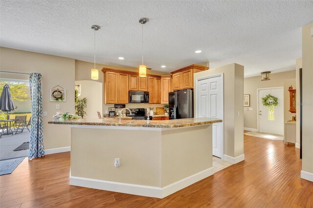 kitchen with pendant lighting, light wood-style floors, black appliances, and recessed lighting
