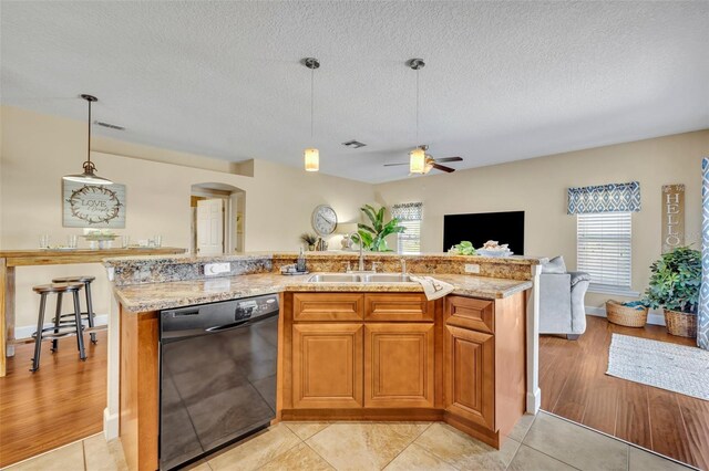 kitchen featuring a ceiling fan, a sink, open floor plan, arched walkways, and dishwasher