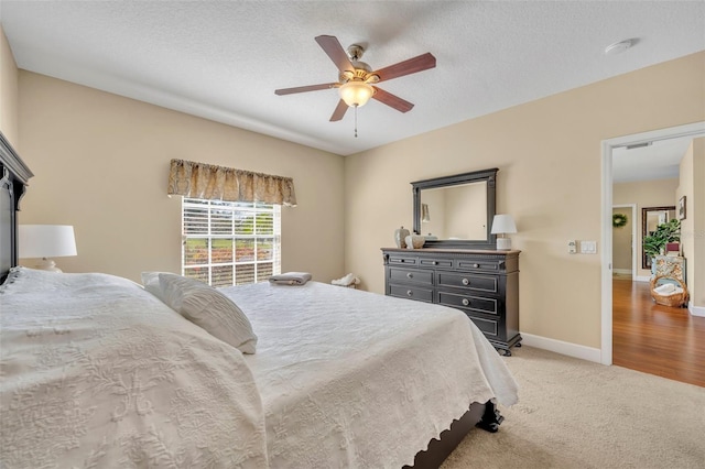 bedroom with visible vents, baseboards, light carpet, a textured ceiling, and a ceiling fan