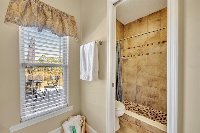 bathroom featuring toilet, a stall shower, and tile patterned flooring