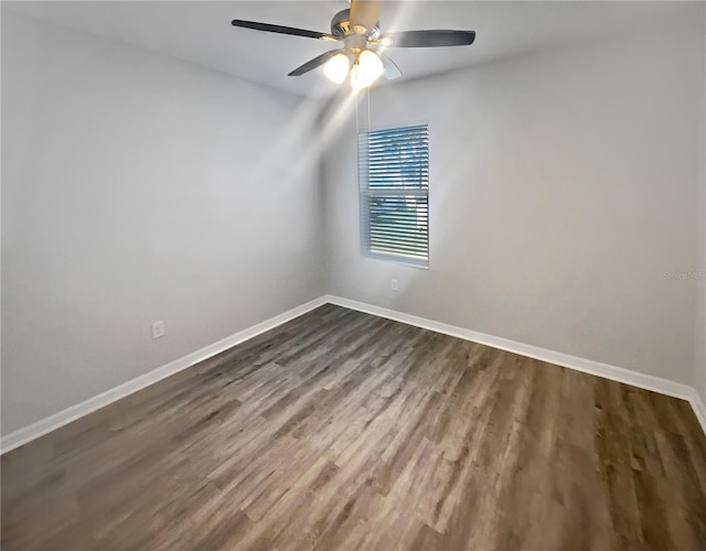 empty room featuring baseboards, dark wood finished floors, and a ceiling fan