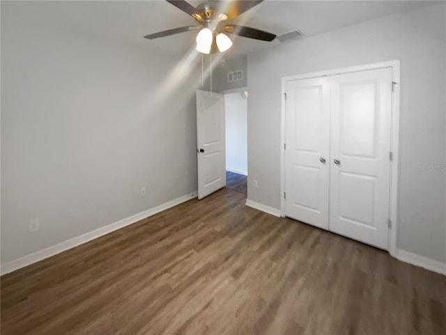 unfurnished bedroom featuring wood finished floors, visible vents, a closet, and baseboards