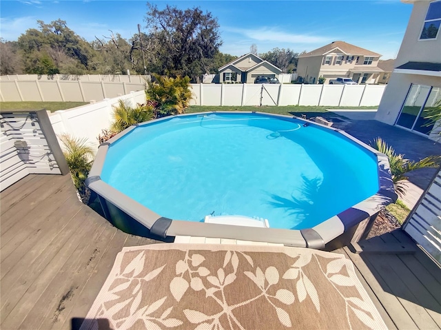 view of swimming pool featuring a deck, a fenced backyard, a fenced in pool, and a residential view