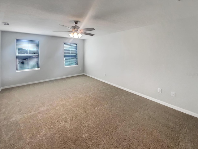 carpeted spare room featuring visible vents, baseboards, and a ceiling fan