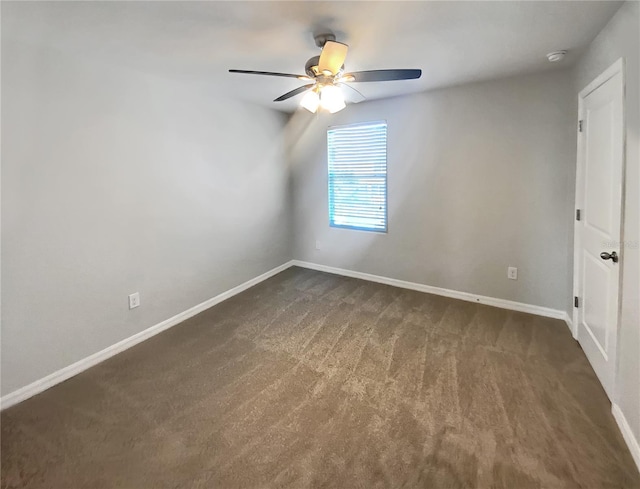 spare room with baseboards, dark carpet, and ceiling fan