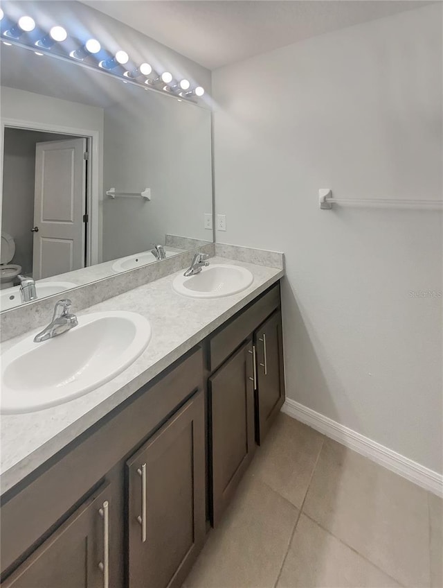 full bathroom with tile patterned flooring, double vanity, baseboards, and a sink